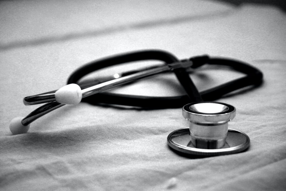 A stethoscope rests on a fabric surface in a black‑and‑white image.