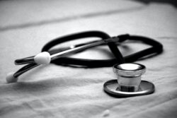 A stethoscope rests on a fabric surface in a black‑and‑white image.