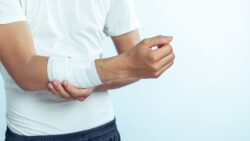 A person holds a bandaged forearm with the opposite hand.