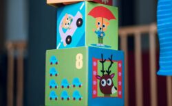 Stacked colourful toy blocks featuring pictures of animals, cars, and numbers.