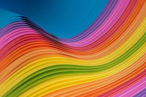 Curved layers of brightly coloured paper arranged in a wave-like pattern.