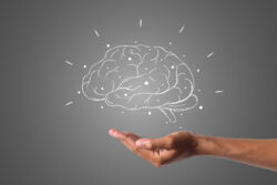A hand is held out with a glowing white outline of a brain floating above it.