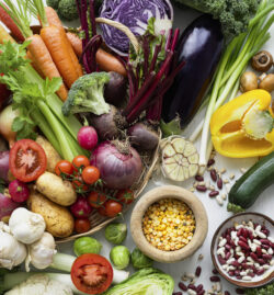 A colourful assortment of fresh vegetables, beans, and pulses arranged on a table.