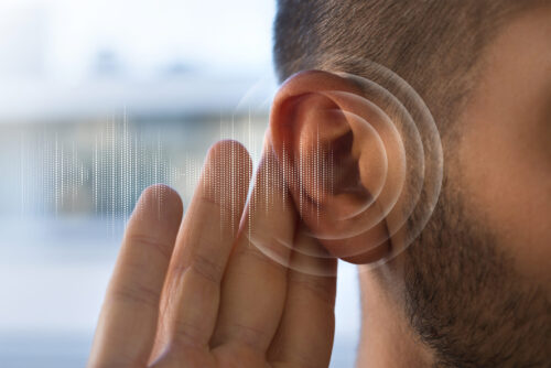 A person holds a hand to the ear with a circular soundwave graphic beside it.